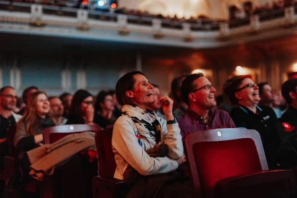 Spectateurs souriants dans une salle, captiv&eacute;s par un &eacute;v&eacute;nement cin&eacute;matographique divertissant.